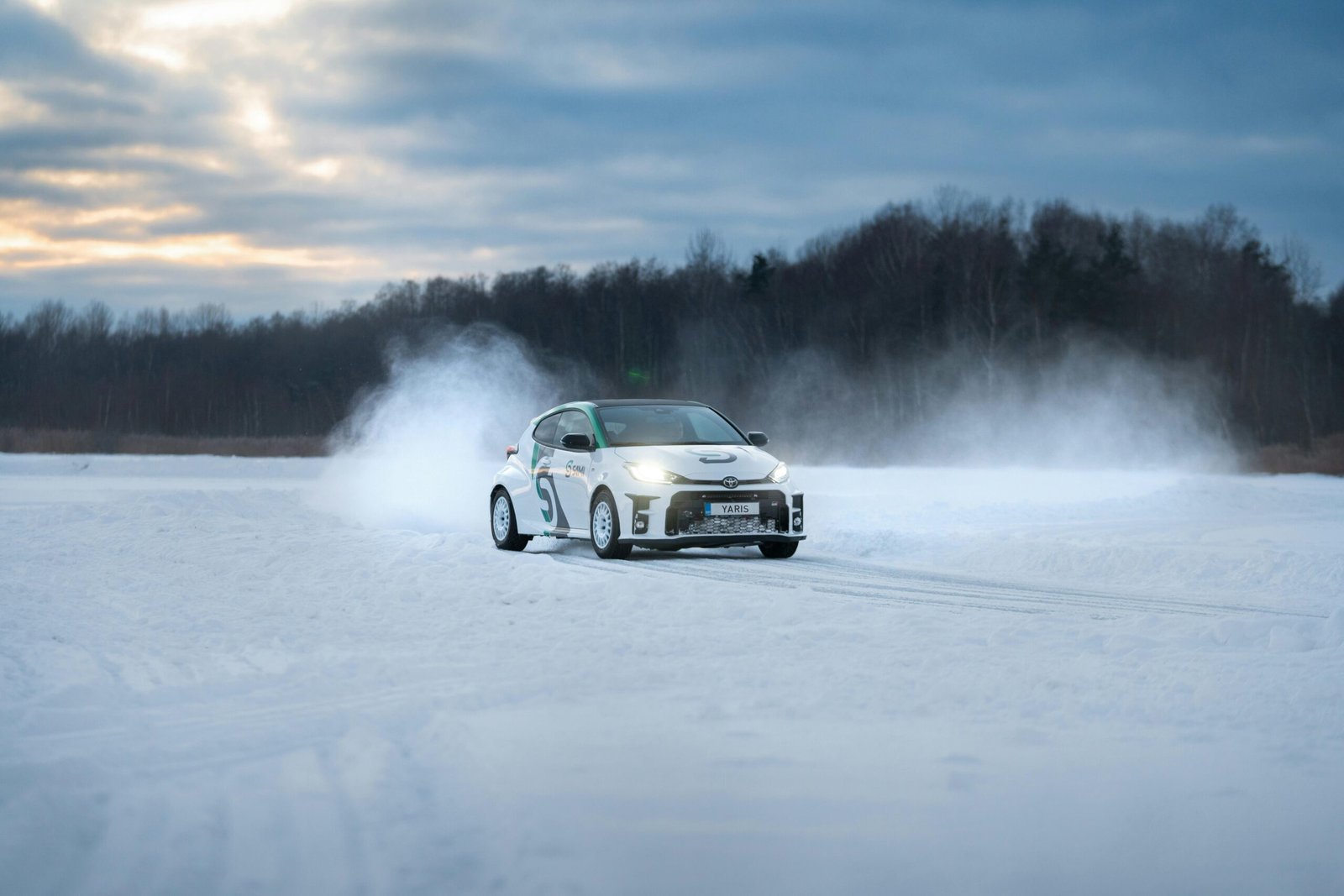 A Toyota GR Yaris performing a thrilling drift on a snowy rural road.