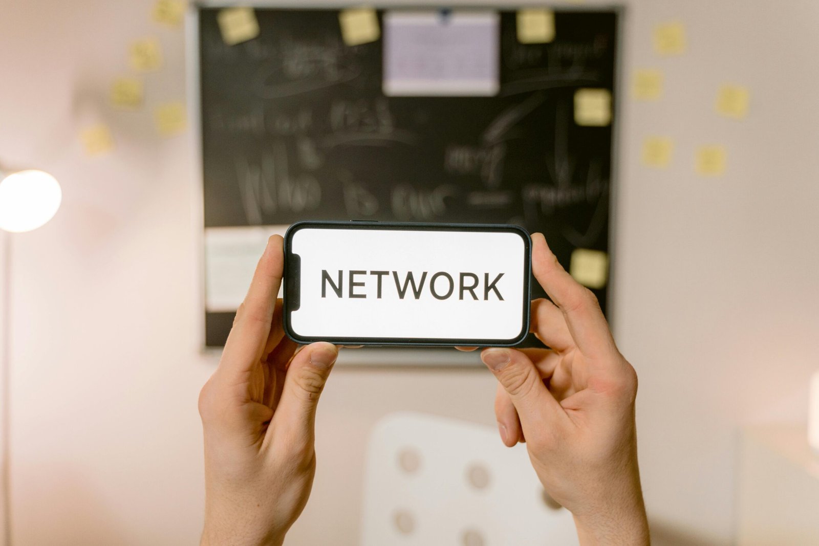 Hands holding a smartphone with 'NETWORK' text on screen, concept of digital communication.