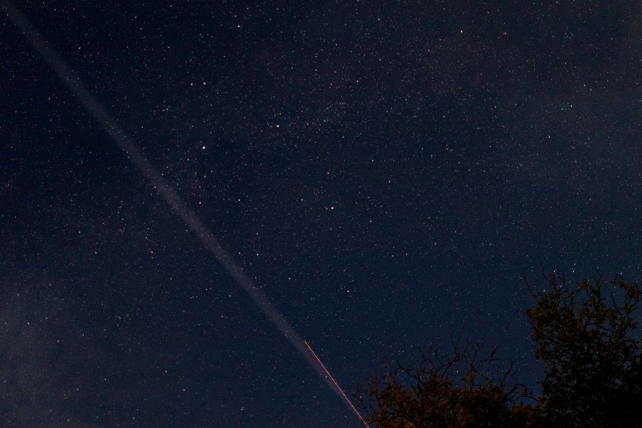 A breathtaking view of a starry night sky with a visible meteor streaking across, captured outdoors.